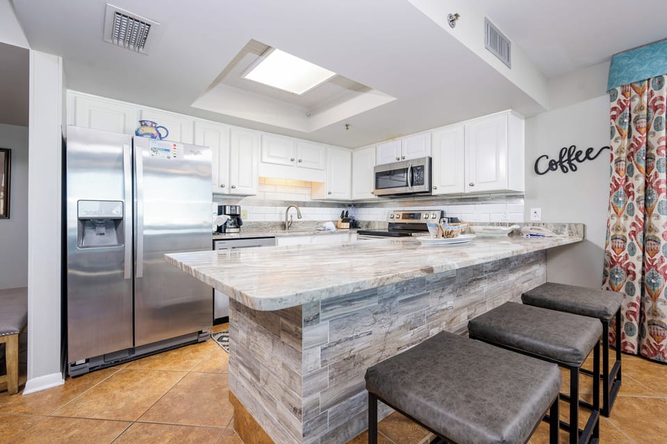 Modern kitchen featuring stainless appliances, granite countertops, and stylish seating for a cozy experience