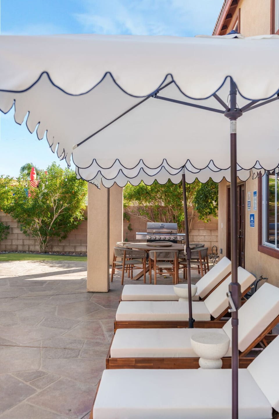 Covered patio dining nook w/ patterned shade, ceiling fan & cozy seating for breezy outdoor meals.