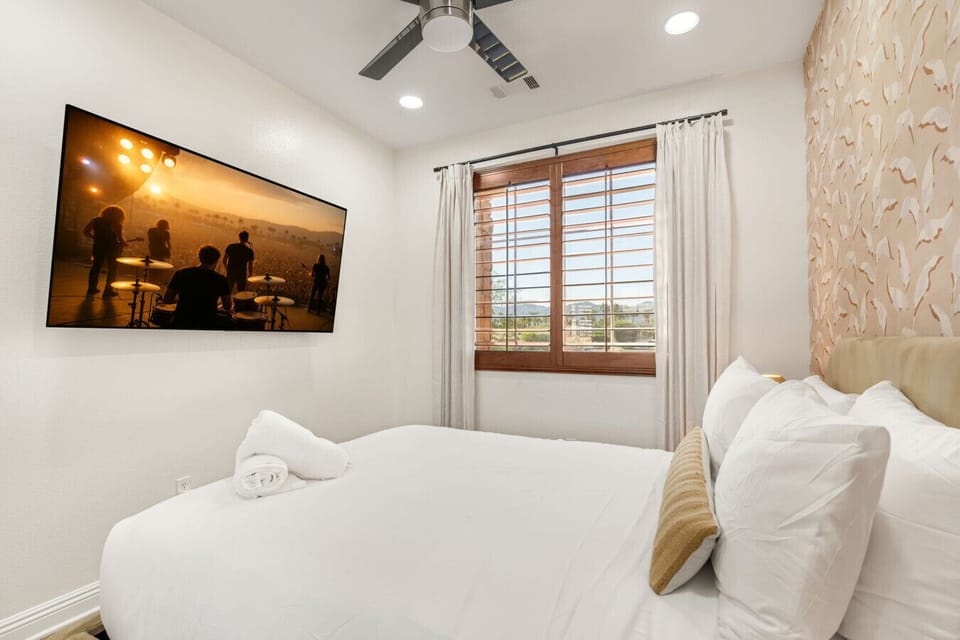 Relaxing bedroom corner w/ wall-mounted TV, plush bedding & warm accents for laid-back evenings in.