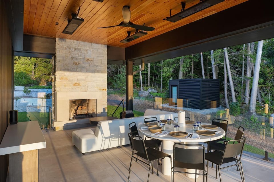 Spacious outdoor patio with cozy fireplace and forest views