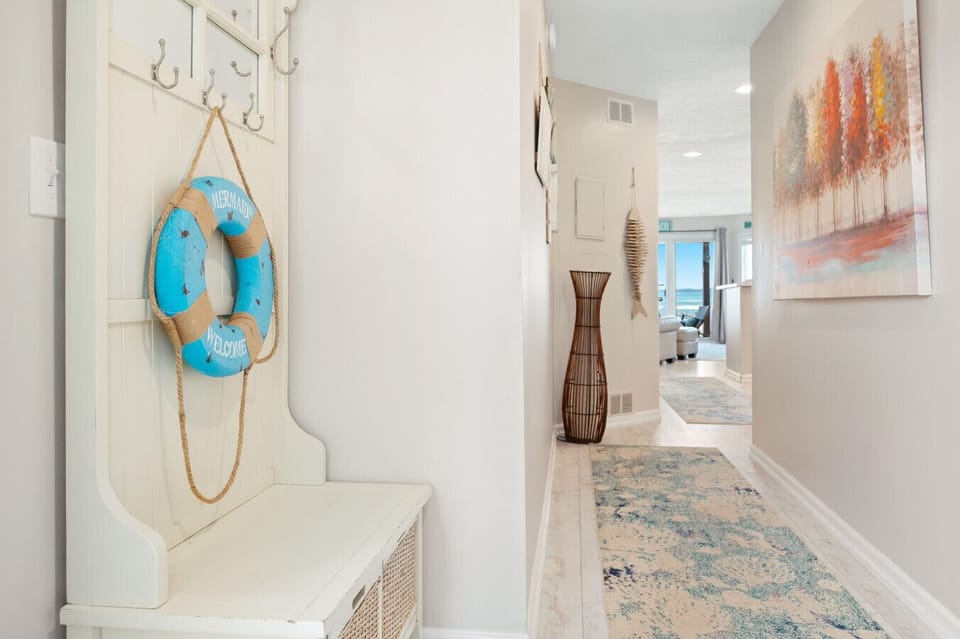 A welcoming entryway with a `Mermaid Welcome` life preserver and a long hallway leading toward the beach. ⚓🌊