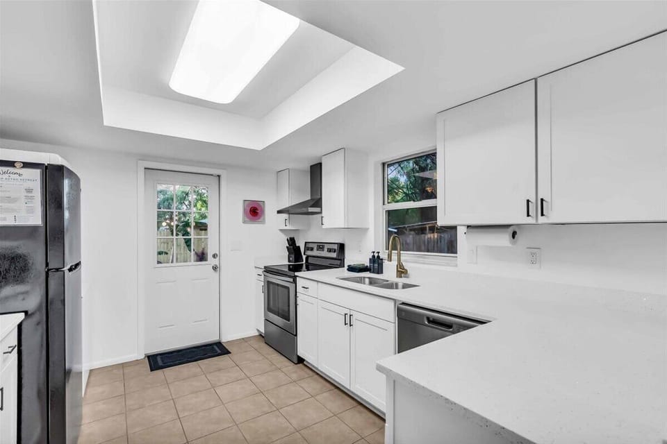 The kitchen has modern appliances like a full-size fridge, microwave, dishwasher, coffee maker, and electric stove.