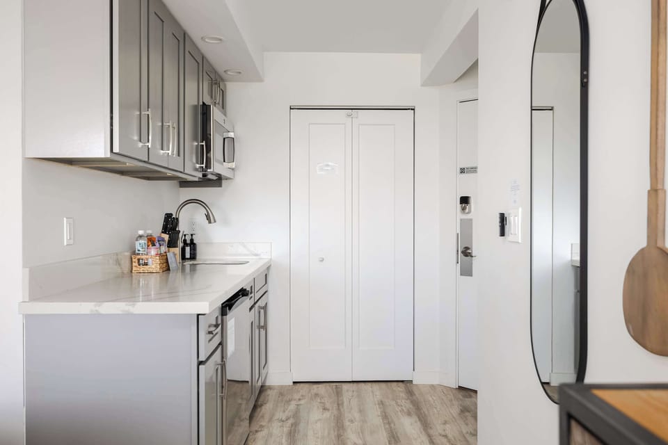 Step into style with your bright, open hallway and modern kitchenette featuring sleek grey cabinets, vinyl flooring, and thoughtful contemporary accents.