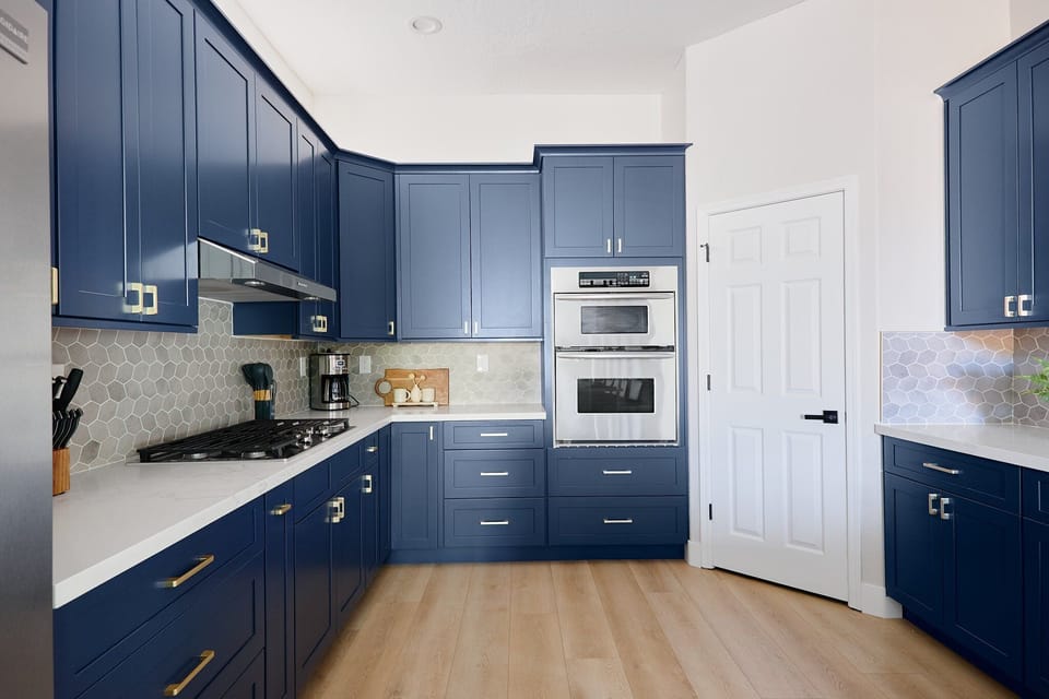 Stylish and functional kitchen with stainless steel appliances, navy cabinetry, marble countertops, and a spacious island with breakfast bar seating for 4.