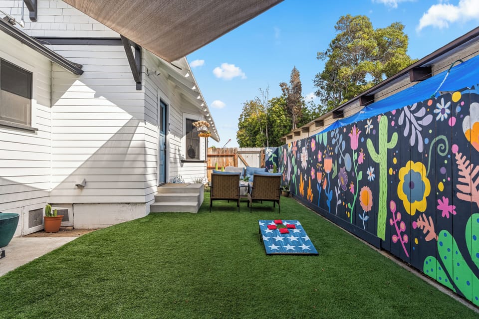 Game on! This unique, fenced-in space features outdoor seating with a cornhole board, complete with an eye-catching mural and turf that stays green all year.