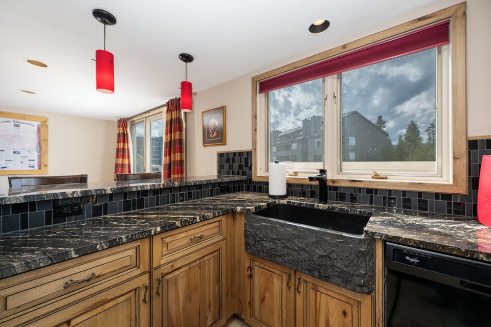 Your alpine kitchen features rich granite counters and rustic wood cabinetry, with mountain views through picture windows.