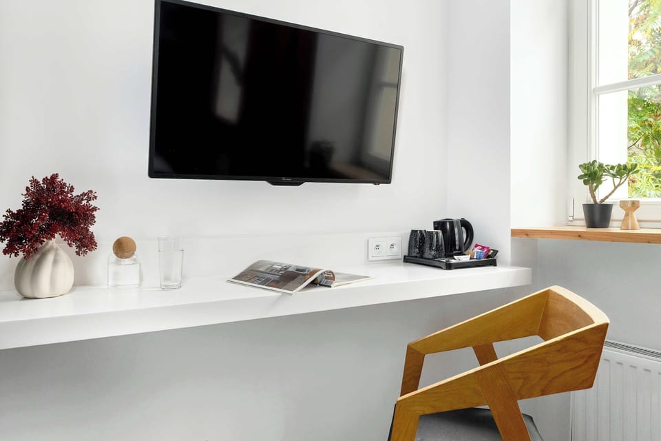 Functional workspace with a desk, TV, and large wardrobe. The big window fills the room with natural light — perfect for work or relaxation.