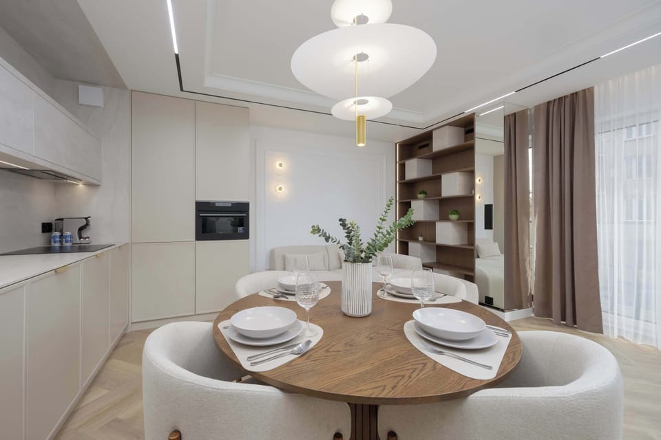 The round dining table surrounded by soft chairs creates an ideal spot for a morning coffee or a romantic dinner in a cozy atmosphere.