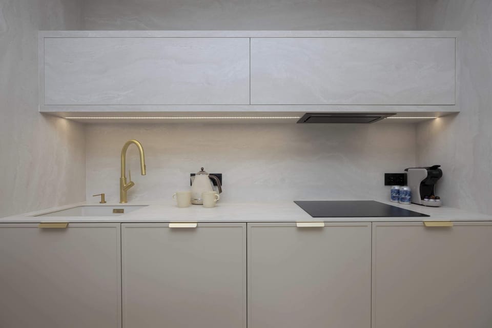 The modern kitchen with sleek cabinets and golden accents invites you to prepare meals in a stylish, perfectly lit space.