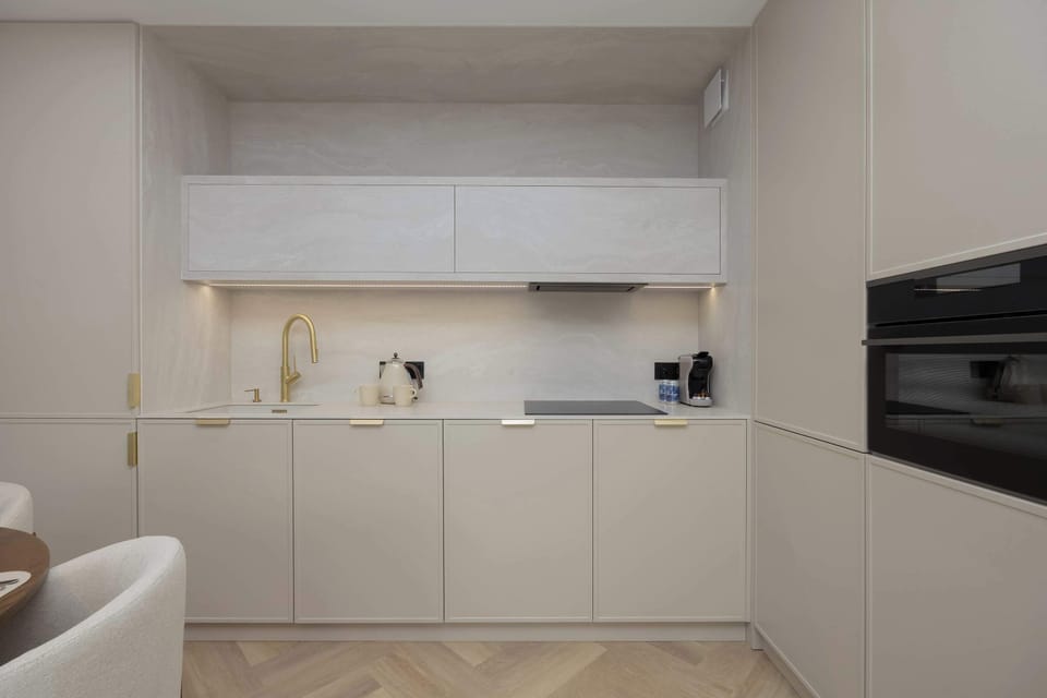 The bright, minimalist kitchen with an elegant countertop and golden details creates a functional space where cooking becomes a pleasure.