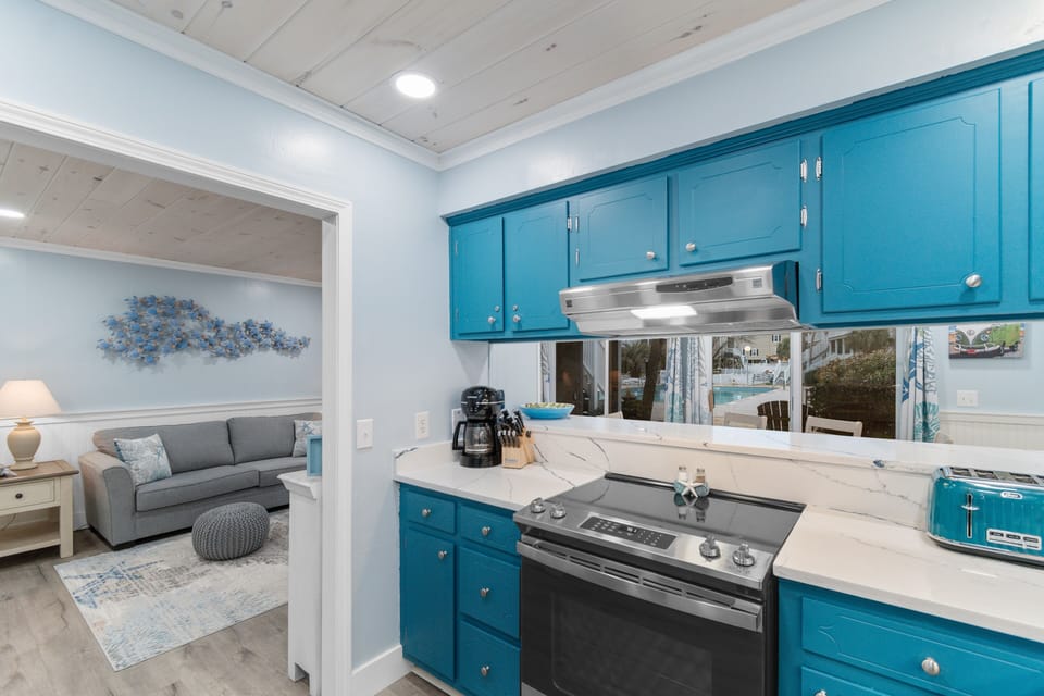 Cook your favorite meals in this charming coastal kitchen featuring vibrant turquoise cabinets and modern appliances.