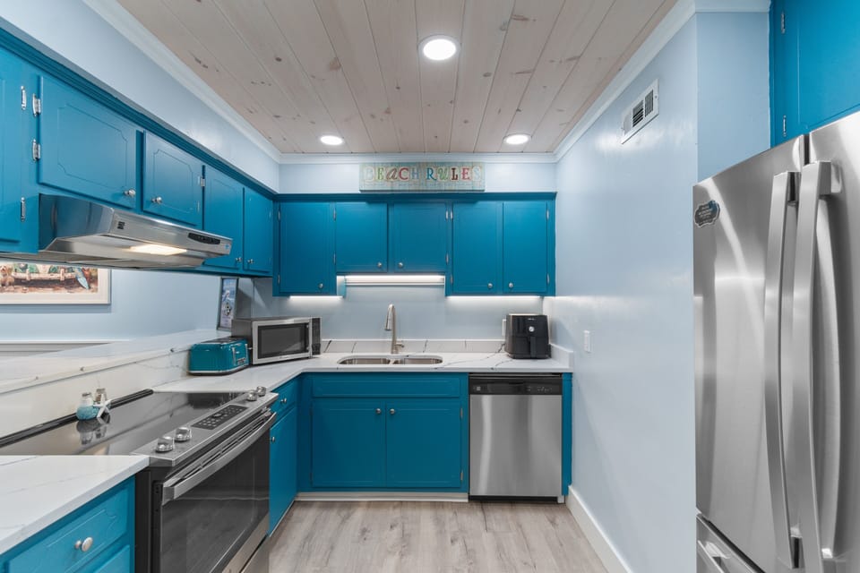 Your fully equipped kitchen features vibrant turquoise cabinets, stainless steel appliances, and marble countertops—perfect for creating memorable meals during your stay.