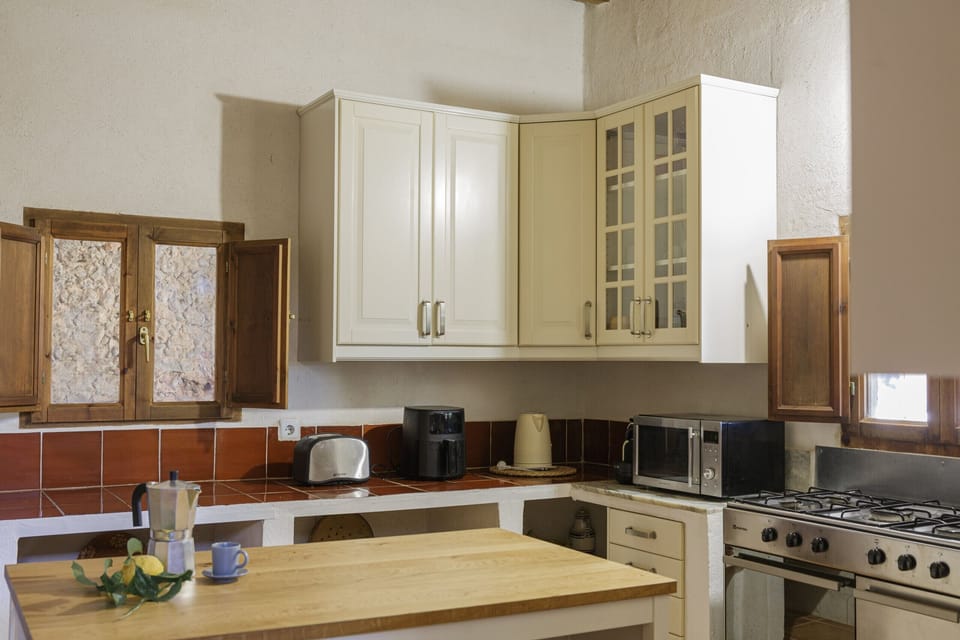 Fully equipped rustic kitchen at Villa Sa Mata with traditional cabinetry, appliances and Mallorcan details.
