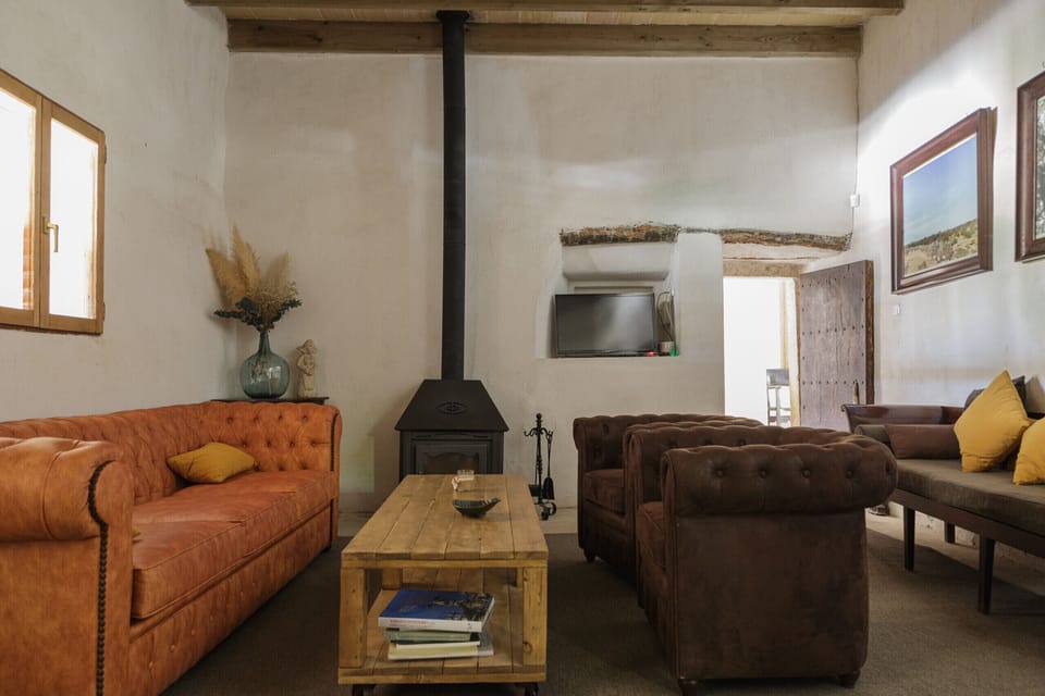 Spacious living room with iron fireplace, leather sofas, and wooden beams that add warmth and authenticity. The perfect place to relax and enjoy the comfort of Mallorcan countryside living.