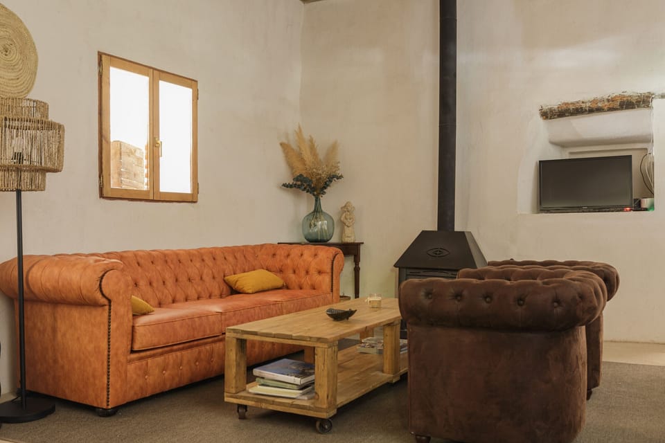 Cozy rustic living room featuring a chester sofa, wood stove and natural décor in a Mallorca holiday villa.