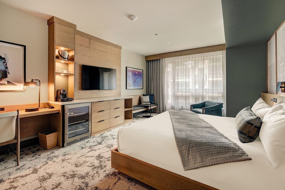 King bed with wall-mounted TV and work desk bathed in natural mountain light