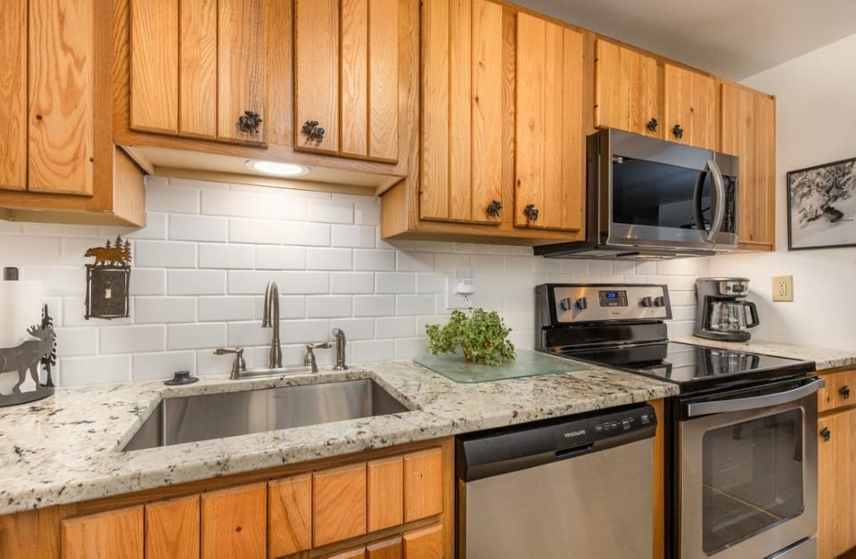 The modern kitchen features rustic wooden cabinets, sleek appliances, and a spacious granite countertop, perfect for meal preparation.