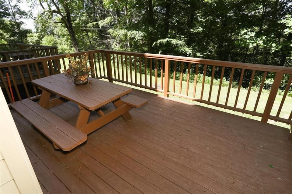 Enjoy serene outdoor moments on the spacious deck equipped with a picnic table surrounded by lush greenery.