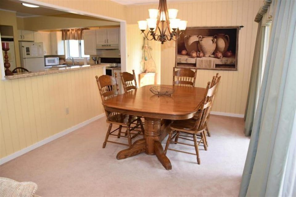 The elegant dining area boasts a large wooden table surrounded by stylish chairs, perfect for family meals or gatherings.