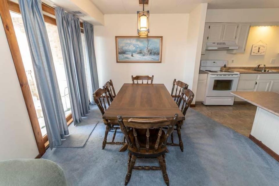 The dining area features a large wooden table surrounded by chairs, offering a perfect gathering spot for meals and conversation.
