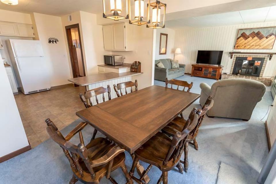The dining area boasts a spacious wooden table surrounded by comfortable chairs, creating an inviting atmosphere for family meals and gatherings.