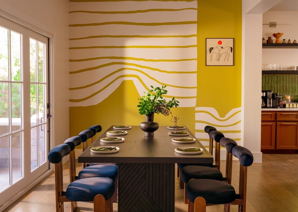  Gather your favorite people around this table. The designer dining room seats 12 beneath a bold yellow mural with natural light at this luxury Texas vacation rental. Ideal for family reunion dinners and group celebrations near DFW.