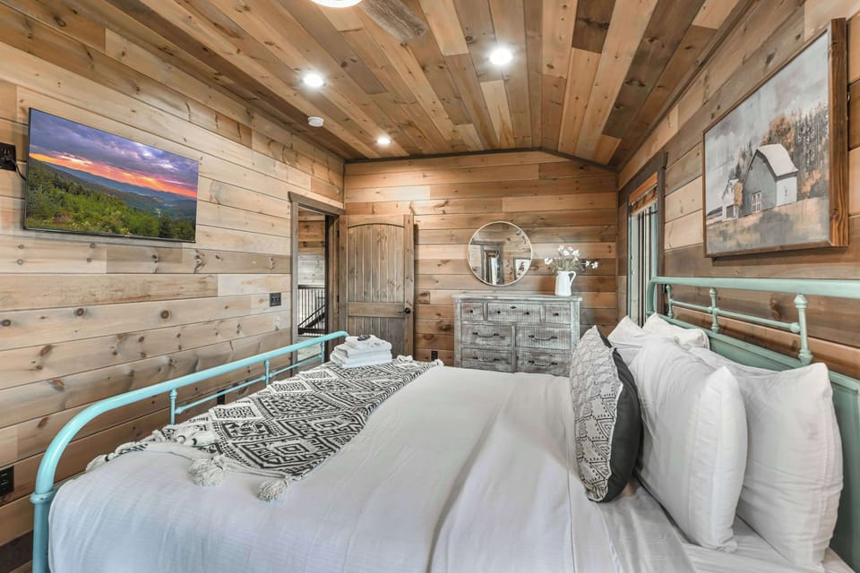 Cozy rustic bedroom with wood-paneled walls and a comfortable bed.