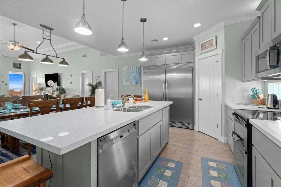 Modern beachfront kitchen with oversized island, stainless steel appliances, and open layout designed for family cooking and entertaining.