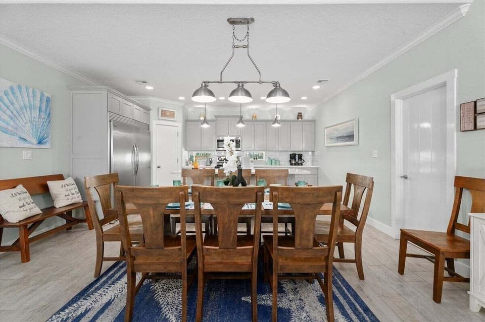 Spacious dining room with farmhouse-style table, coastal décor, and open floor plan perfect for family dinners and group gatherings by the beach.