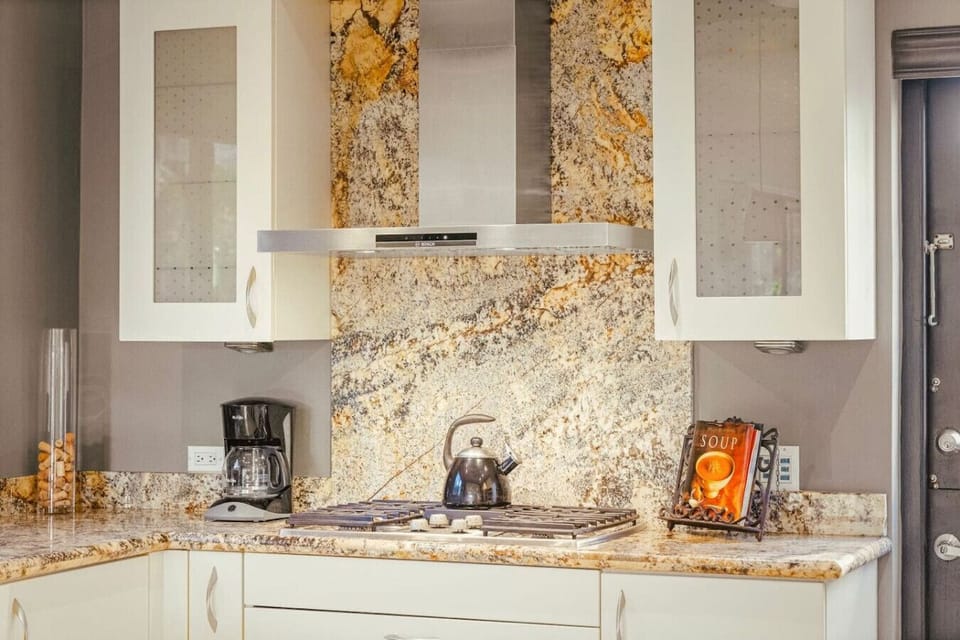 A stunning granite backsplash meets modern appliances — warmth and luxury blend in perfect culinary harmony.