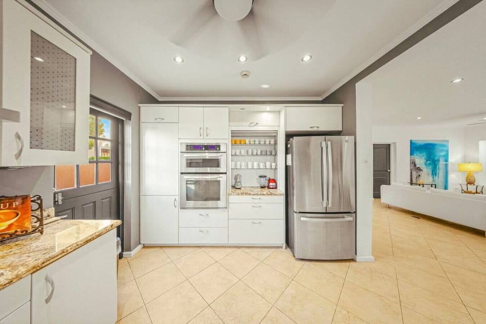 Sleek white cabinetry, modern appliances, and warm granite tones create a bright, inviting culinary hub.