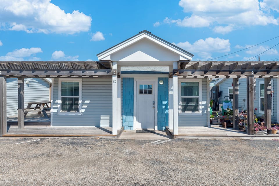 Charming coastal cottage with blue accents and covered porch, perfectly positioned for your seaside getaway.