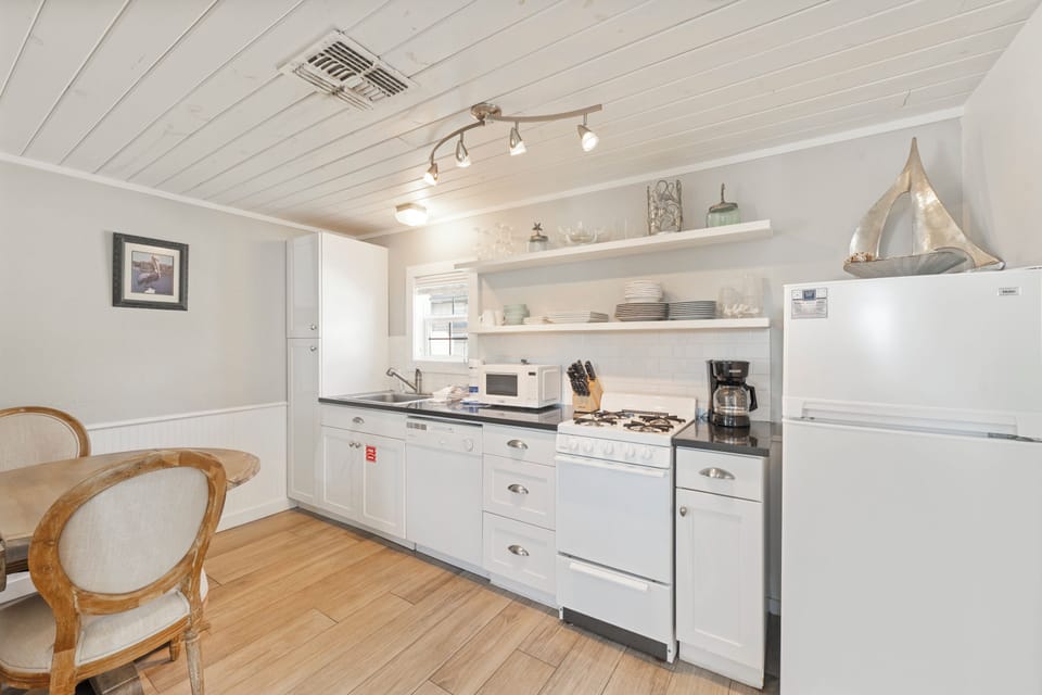 Your charming galley kitchen features everything you need, from crisp white cabinets to modern appliances and cozy dining nook.