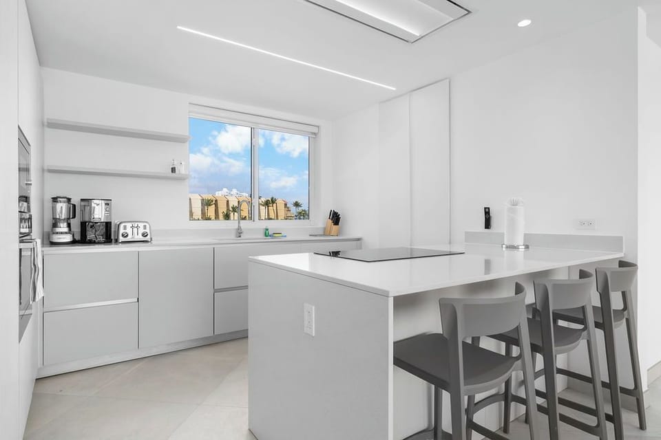 Modern kitchen with sleek design and breakfast bar seating for your convenience. Natural light flows through large windows while you prepare meals with quality appliances.