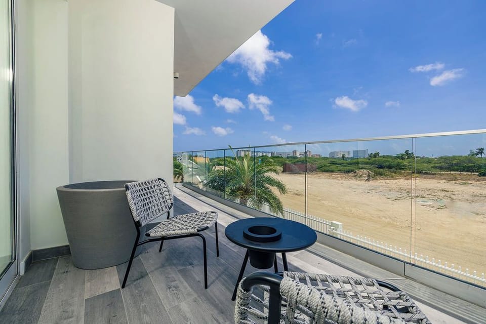 The exterior view beyond the property shows undeveloped land with distant city buildings on the horizon, surrounded by tropical vegetation and expansive open terrain.