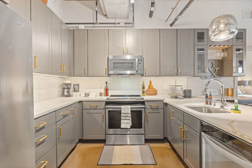Your sleek modern kitchen features premium stainless steel appliances and elegant gray cabinetry with gold hardware for effortless meal preparation.