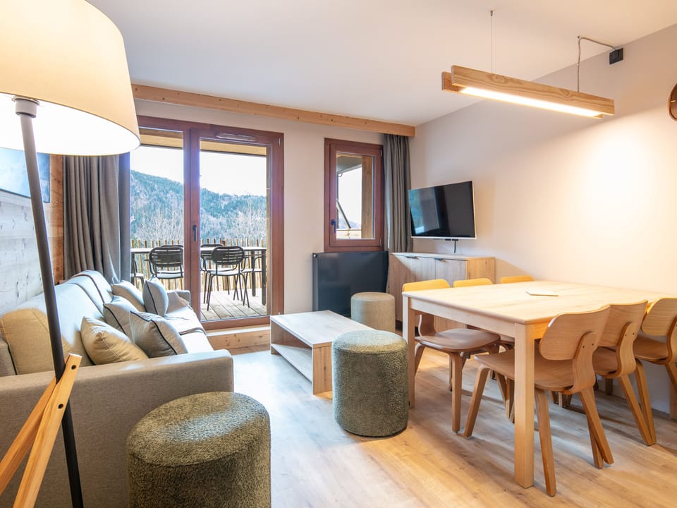 Gather around the modern dining table for meals, while the large windows flood the space with natural light.