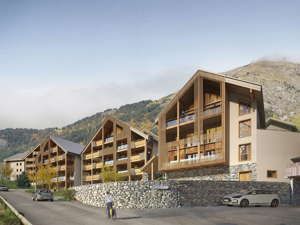 Contemporary alpine residence with wooden facades and sweeping mountain views under clear skies.