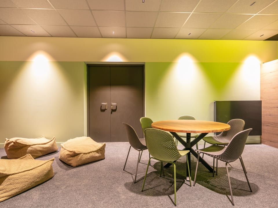 Gather around a sleek table in a chic meeting space, complete with bean bags for a relaxed vibe.