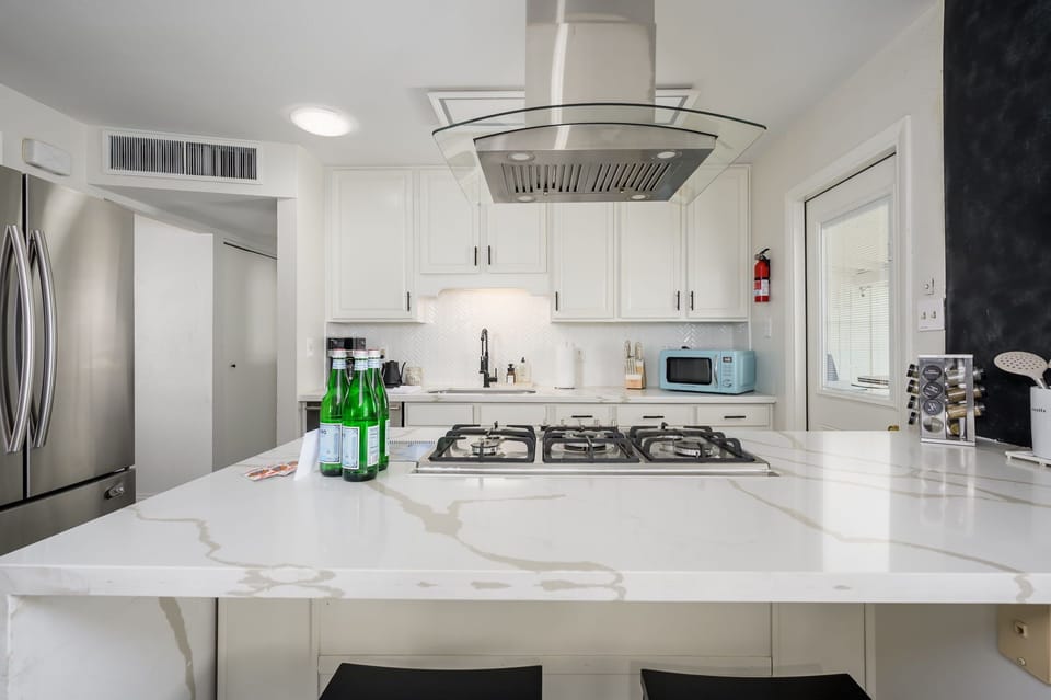 Cook and entertain in this light, modern kitchen featuring sleek quartz countertops, stainless steel appliances, and a large island—perfect for gathering, prepping meals, or drinking morning coffee together.