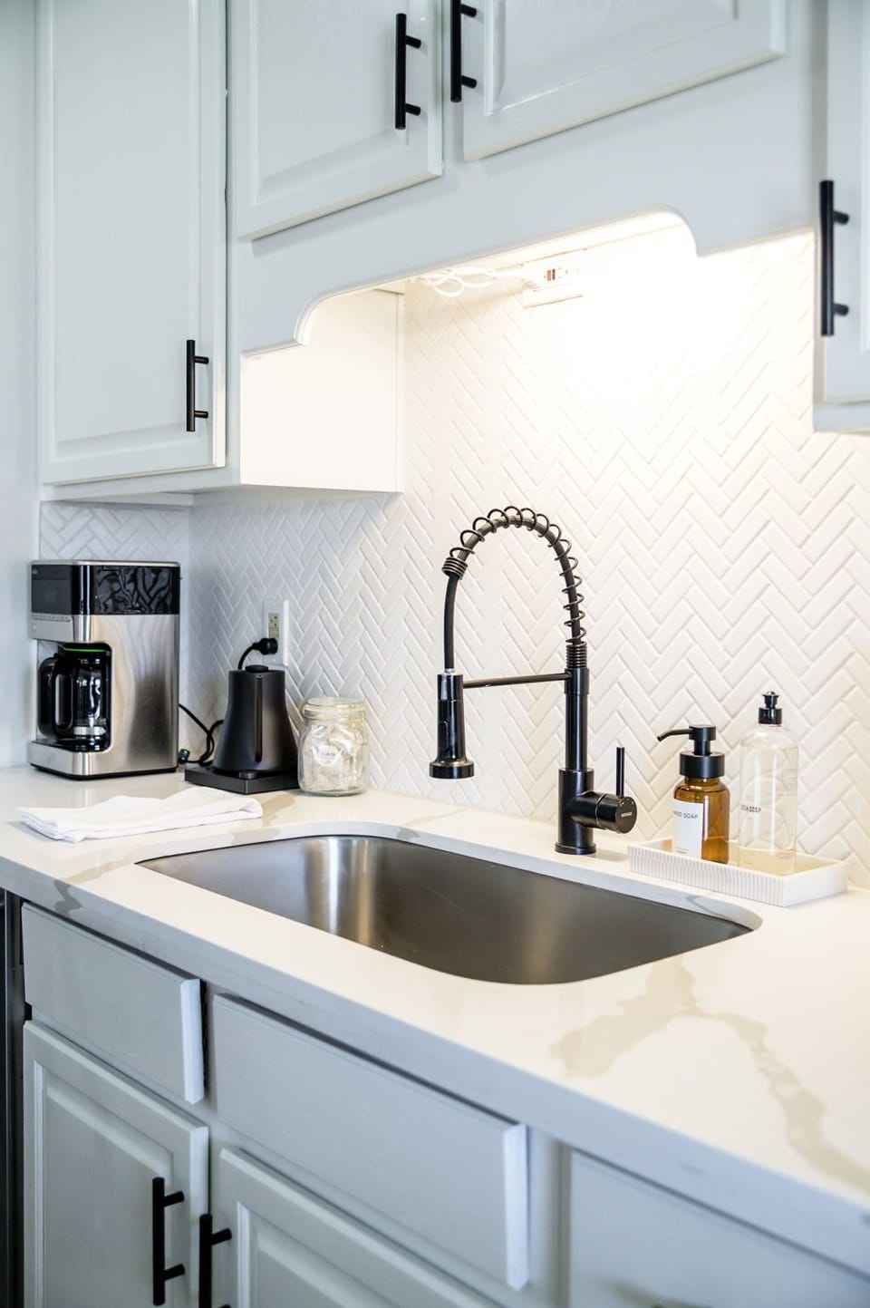 Start your morning with ease in this well-equipped kitchen nook, complete with a sleek modern sink, coffee maker, and electric Fellow kettle—perfect for brewing your favorite cup before heading out for the day.