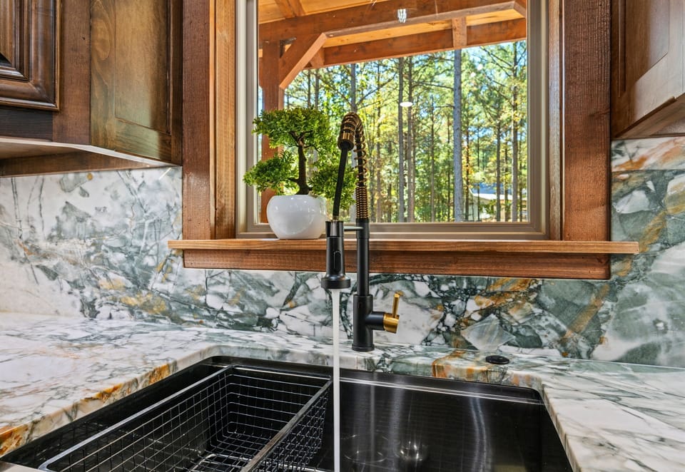 Large farmhouse sink and scenic kitchen window views.