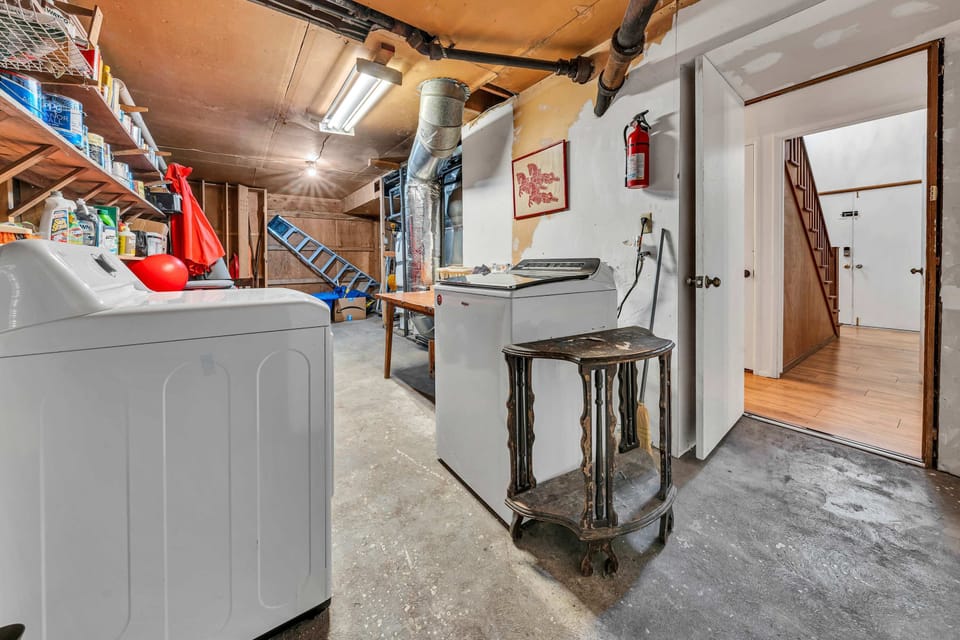 Spacious utility and laundry area featuring top-loading machines and ample shelving for guest use.