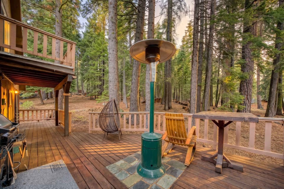 Deck: Forest-view deck with patio heater, gas grill, Adirondack chairs, bistro table, and hanging wicker egg chair ideal for relaxing among the pines