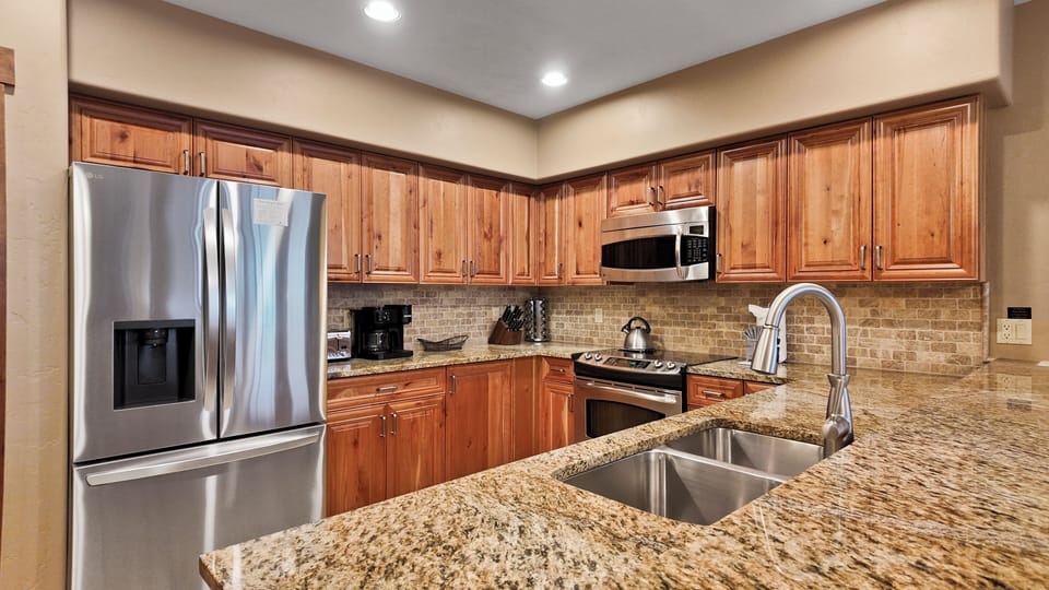 Granite countertops and stainless appliances in full kitchen.