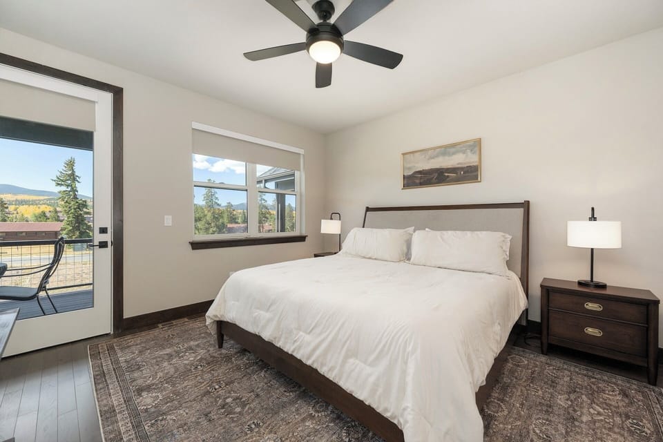 Main level master suite with king bed, door to patio, TV, and ensuite bathroom