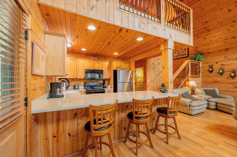 Open-concept cabin with cozy seating, loft access & warm wood finishes.