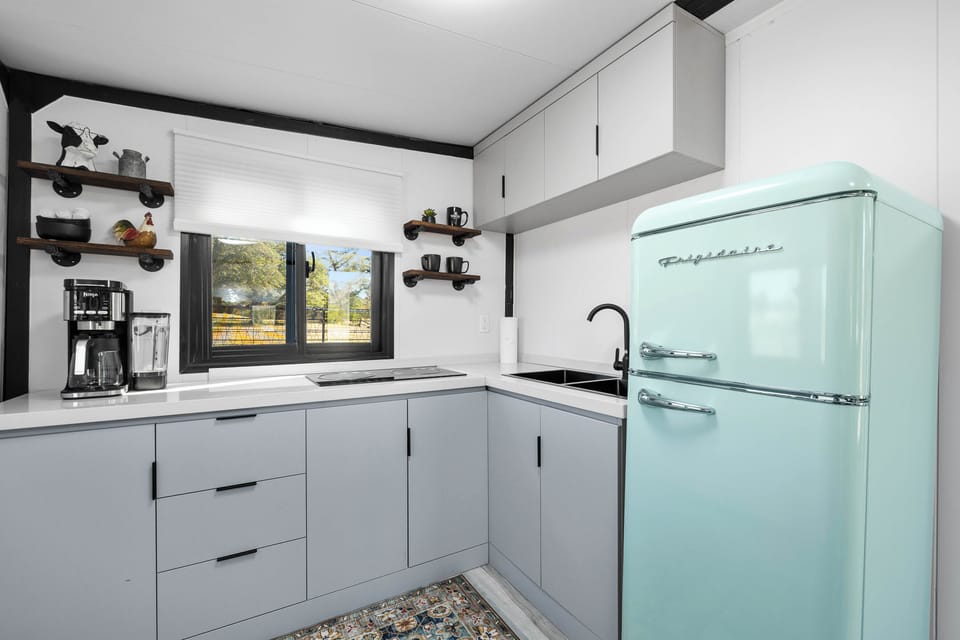 A bright, modern kitchen with a retro mint fridge and peaceful farm views-perfect for morning coffee or a cozy night in.