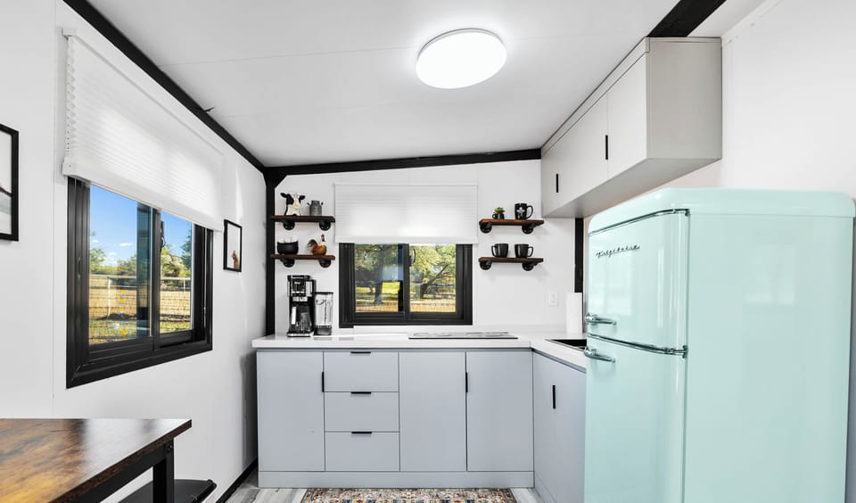 A bright, modern kitchen with a retro mint fridge and scenic farm views-perfect for your morning coffee in Prescott.