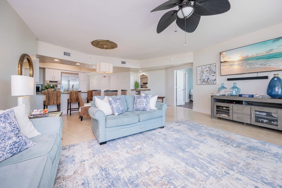 Cozy living area featuring a cozy blue sofa, stylish decor, and a view of the modern kitchen